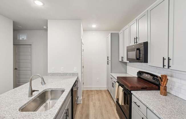 A kitchen with a sink, stove, and cabinets.