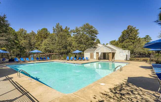 A large swimming pool surrounded by trees and a building in the background.