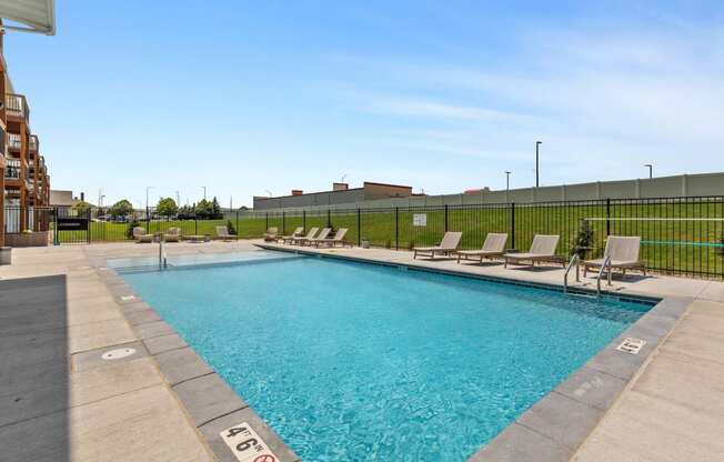 a swimming pool with lounge chairs and a building in the background