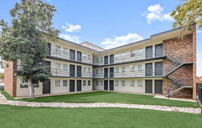 an exterior view of an apartment building with grass and trees at The Courts Midtown, Memphis