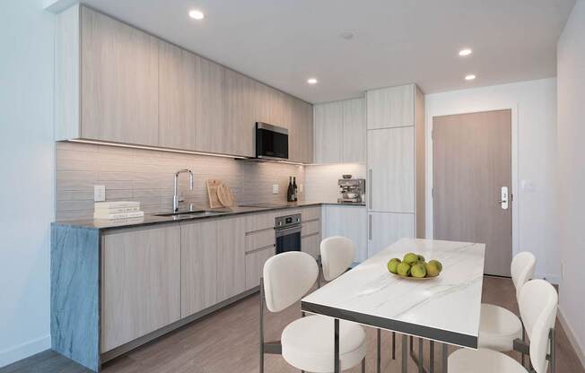 A modern kitchen with a dining table set with fruit.