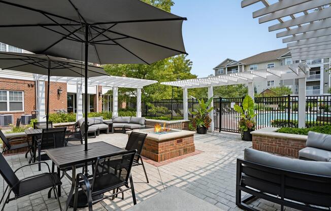 Outdoor courtyard with dining tables, lounge seating, and a central fire feature, creating a welcoming setting.