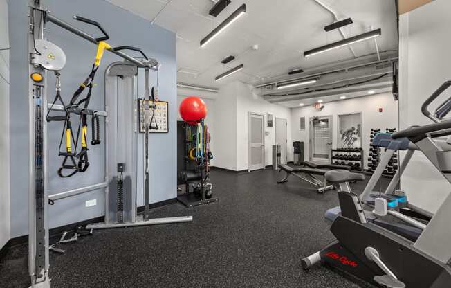 a gym with weights and other equipment on the floor and a red ball in the