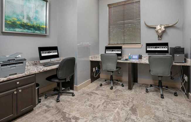 A room with a desk, chairs, and a painting on the wall.