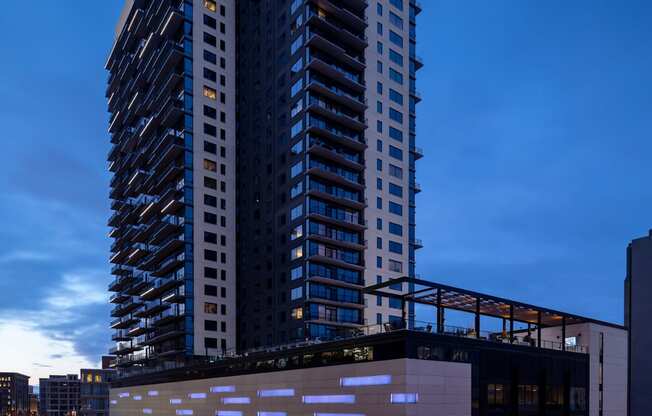 A modern building with a unique design is lit up at night.