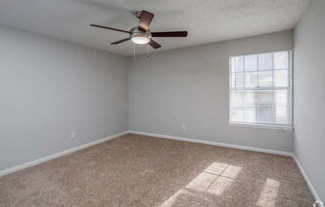 an empty room with a ceiling fan and a window