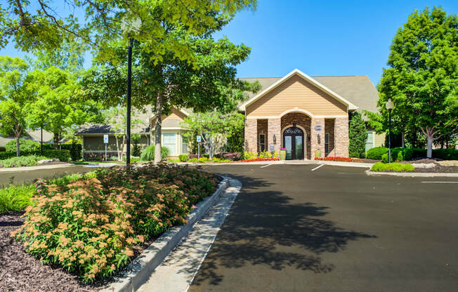 A building with a brown roof and a black door is surrounded by greenery.