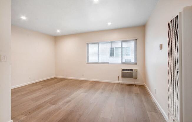 an empty living room with wood floors and a window