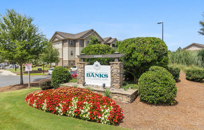 A sign for Banks in front of a building with a flower bed in the foreground.