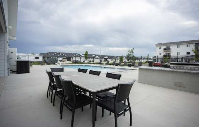 a patio with a dining table and chairs next to a pool