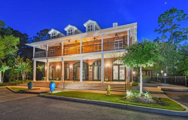 a house with a large porch and a tree in front of it at Lagniappe of Biloxi Apartment Homes, Mississippi
