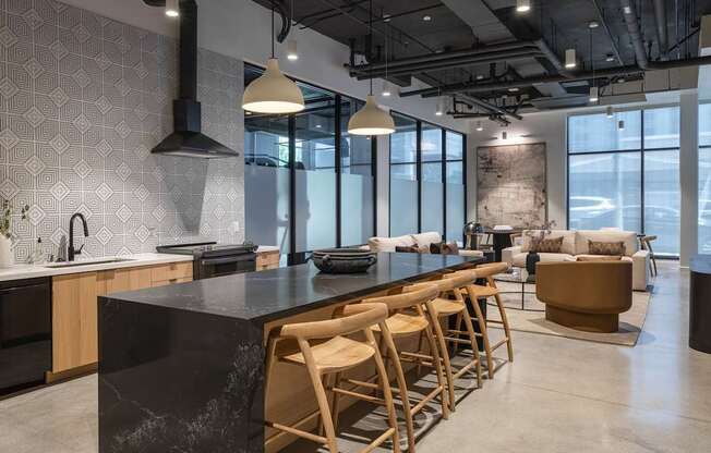 A modern kitchen with a black countertop and wooden chairs at Skylar At Sunset Apartments, Los Angeles, California