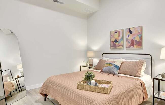 A bedroom with a bed, nightstand, and a painting on the wall.