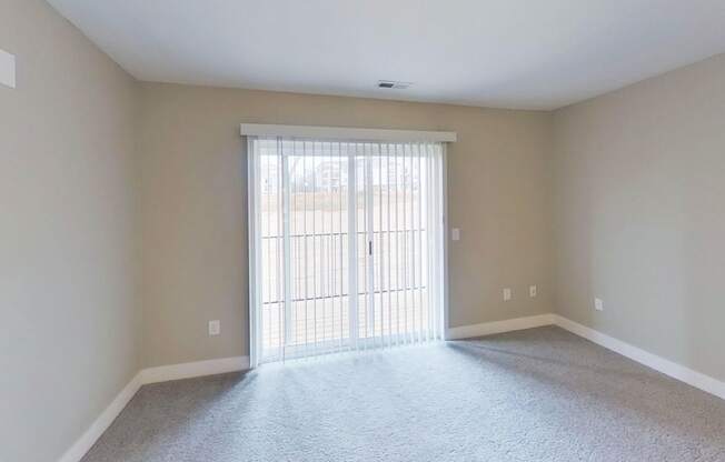 living room with a slider to a balcony end kitchen with a window at Signature Pointe Apartment Homes in Athens, AL