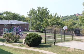 a playground with a basketball hoop and basketball hoop in front of a brick building