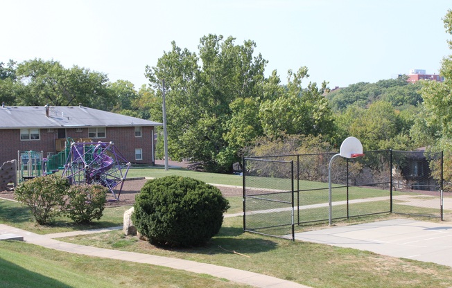 a playground with a basketball hoop and basketball hoop in front of a brick building