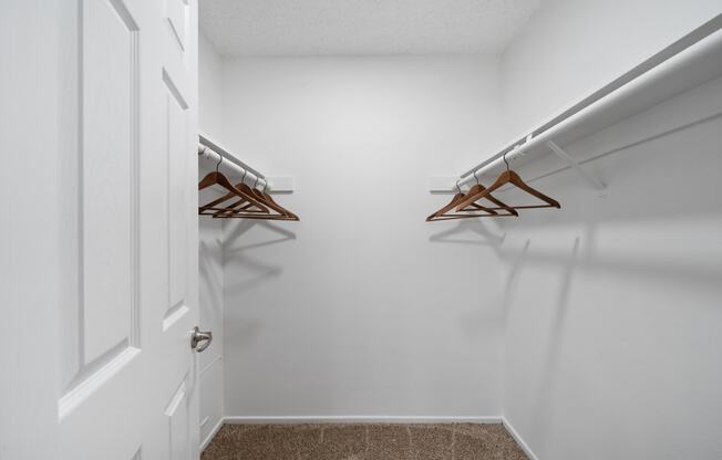 a walk in closet with two hanging racks and a white door