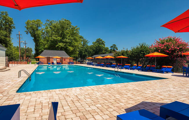 our resort style swimming pool is surrounded by lounge chairs and umbrellas