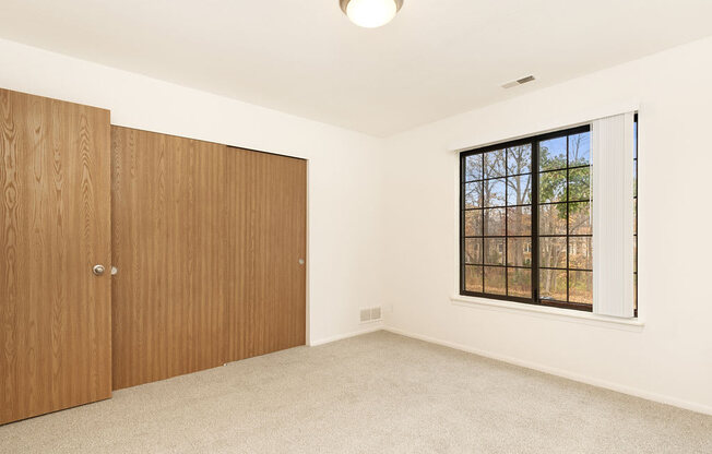 an empty bedroom with a window and a door