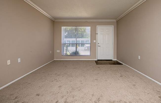 A room with a carpeted floor and a door leading to a balcony.