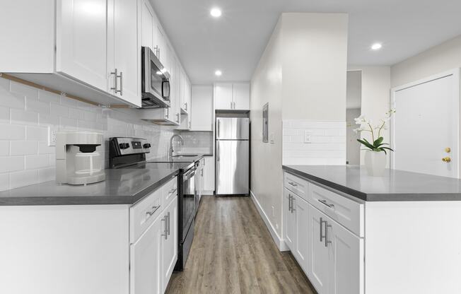 a white kitchen with white cabinets and black counter tops