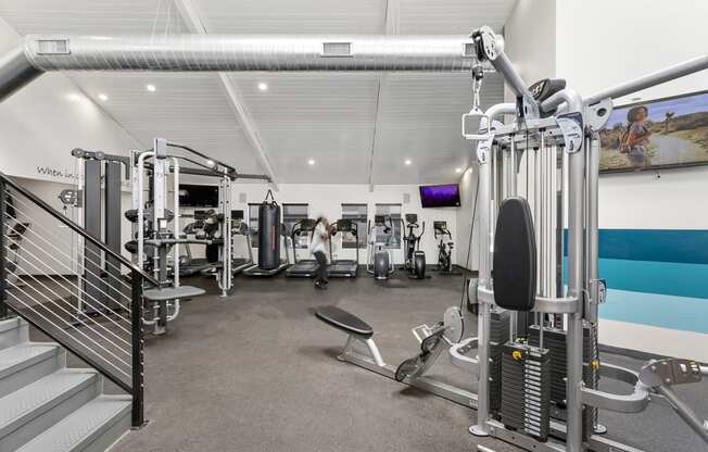 a gym with weights and cardio equipment and a staircase