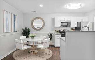 a dining area with a table and chairs and a kitchen in the background