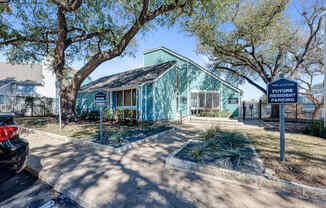 A blue sign in front of a house reads "Resident Parking".