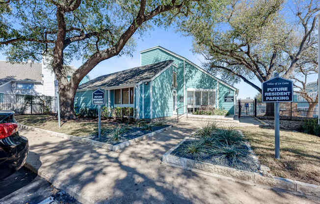 A blue sign in front of a house reads "Resident Parking".