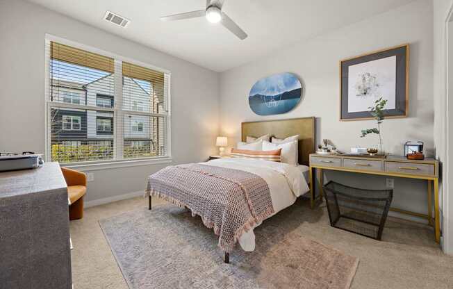 A bedroom with a bed, desk, chair, and window.