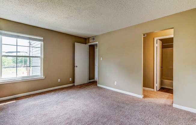 an empty living room with a large window and carpet