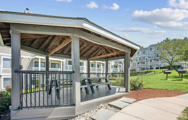 A wooden covered patio with a black railing and benches.