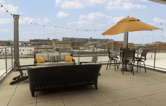 a rooftop patio with a couch and chairs and an umbrella