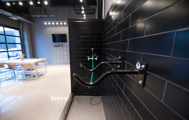 A black tiled wall with a handrail and a green hose attached to it.