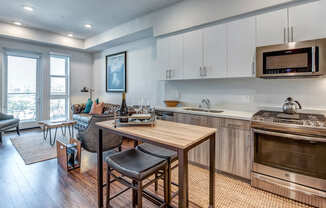 A modern kitchen with a wooden table and bar stools.