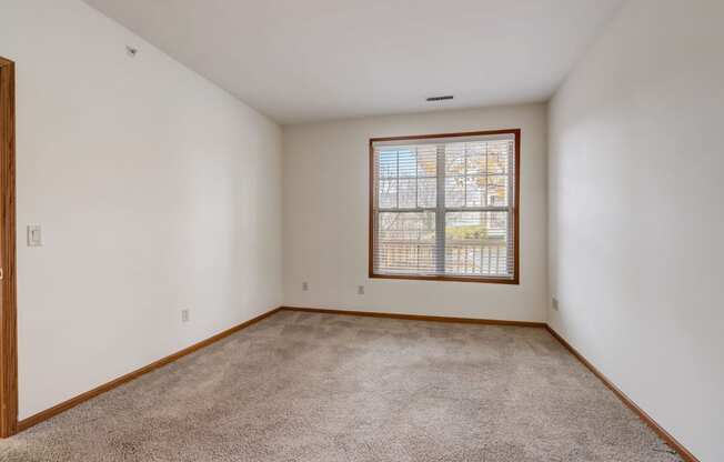 an empty living room with a window and carpet