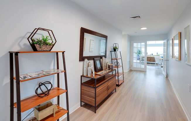A long hallway with a wooden floor and a mirror on the wall.