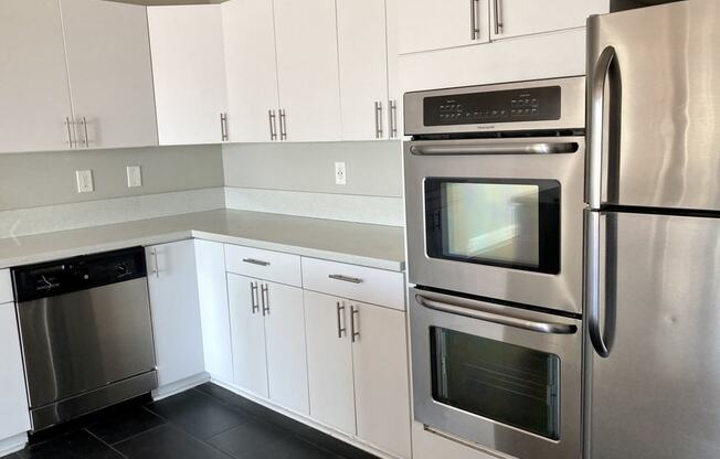 A modern kitchen with white cabinets and stainless steel appliances.