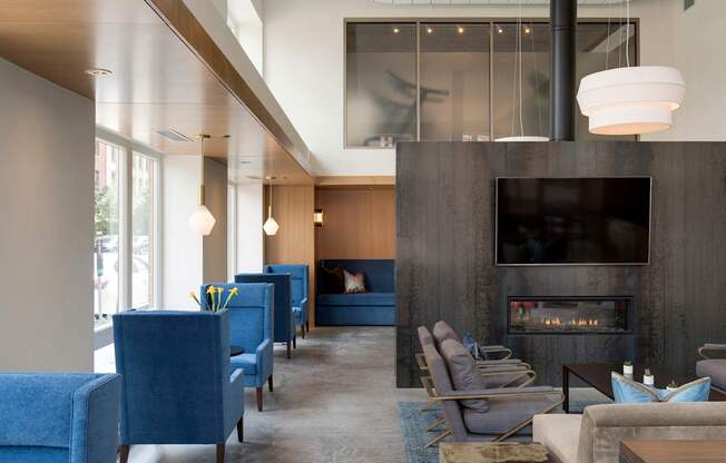 A modern living room with a fireplace and blue chairs.