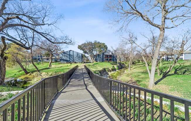 A wooden walkway leads through a park with trees on either side.
