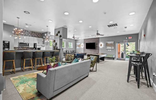 A living room with a grey couch and a kitchen area in the background.