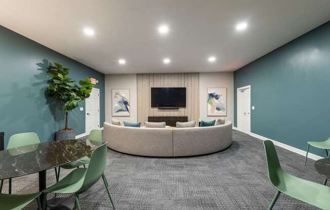 A modern living room with a grey carpet and a round sofa.