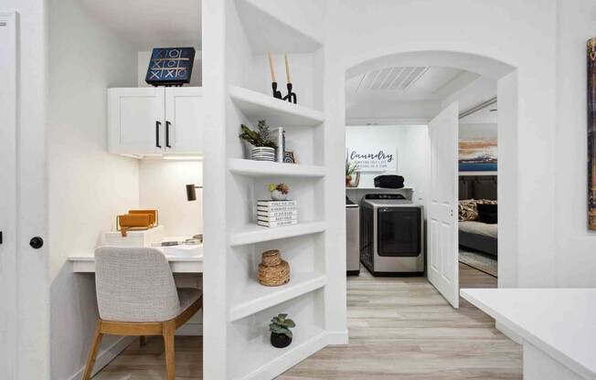 a home office with a white desk and chair next to a white bookshelf with a