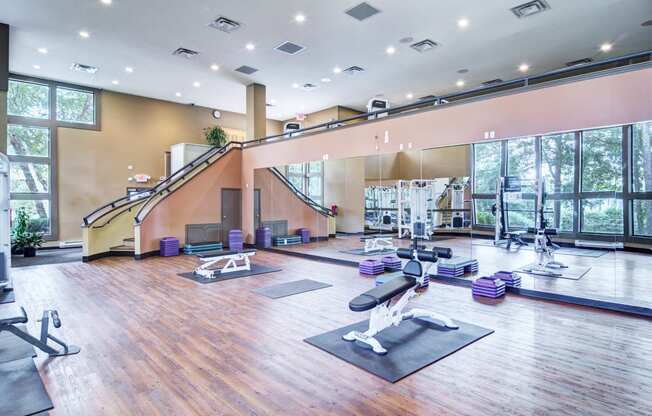 a spacious fitness room with yoga mats and exercise equipment and large windows
