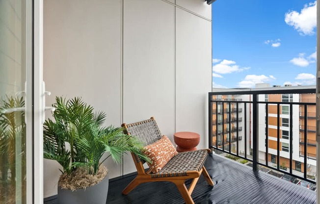 A balcony with a chair, potted plant, and a cushion.