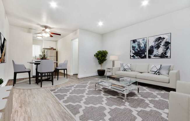 A living room with a white couch, a grey rug, and a ceiling fan.