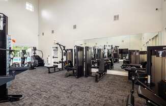 a gym with cardio equipment and mirrors on the wall