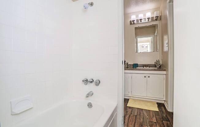 A white bathroom with a tub and a mirror at The Drake in Bossier City, LA
