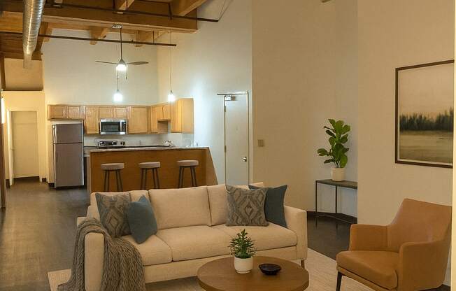 A living room with a white couch, a wooden coffee table, and a brown chair.