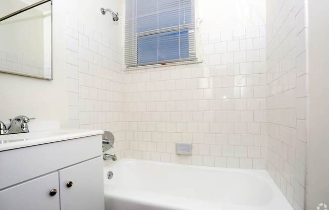 A white bathroom with a tub, sink, and mirror.